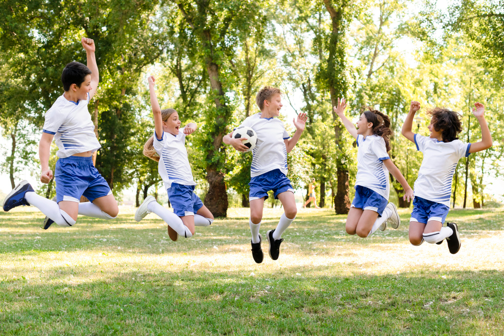 Kids in football team jumping on grass field