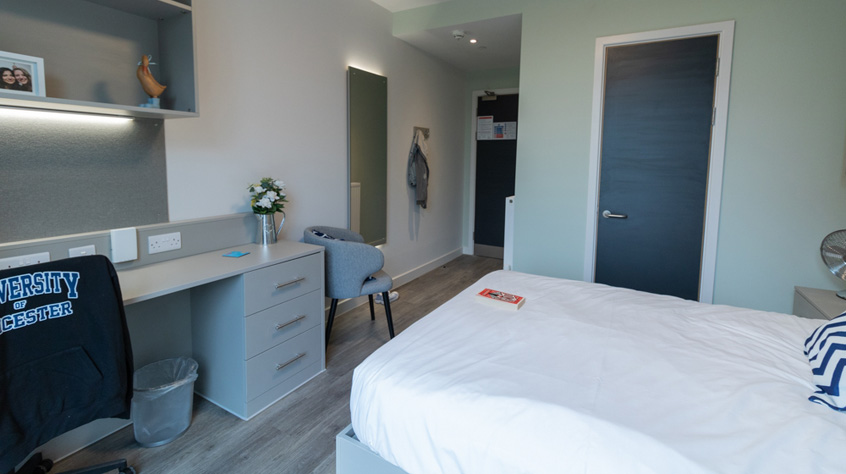 en-suite student room with bed, mirror, grey desk and chair