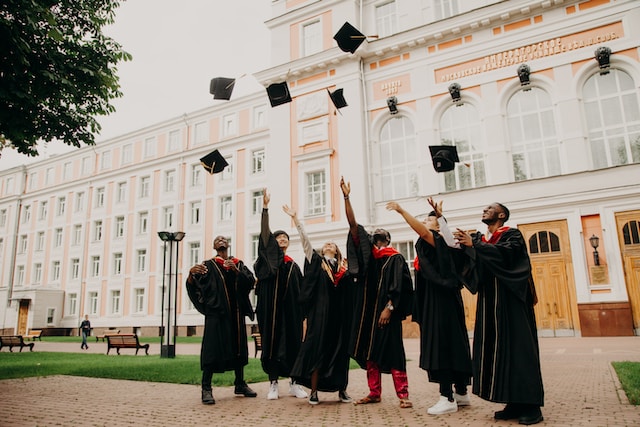 university students throwing hat at graduation