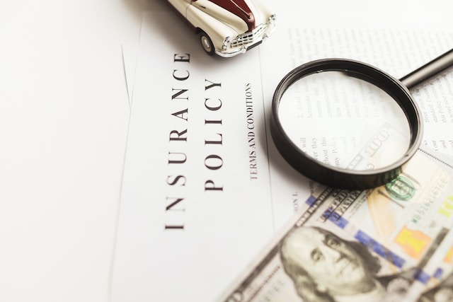 insurance policy with toy car, money and magnifier