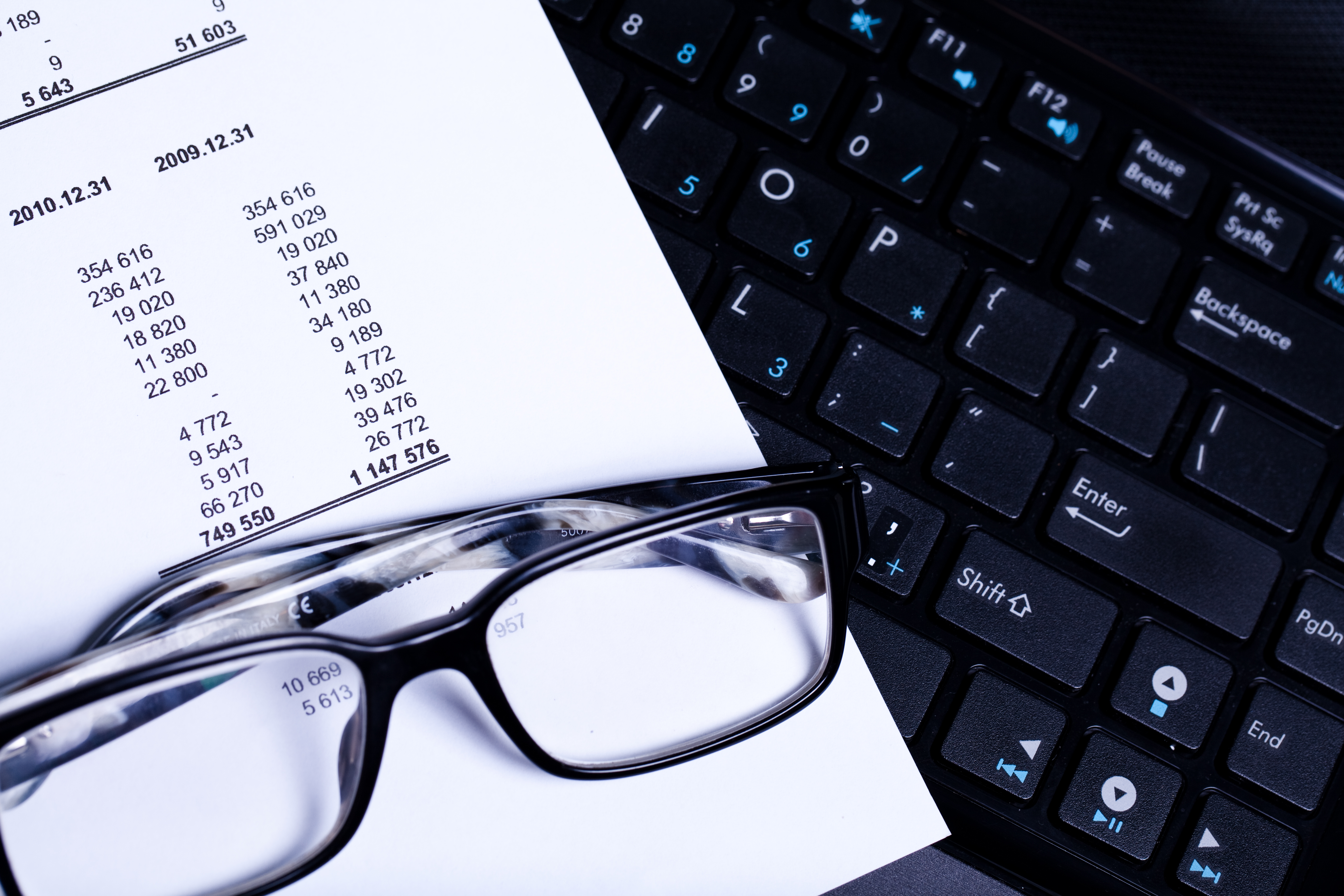 Bank statement laying on laptop keyboard with glasses 