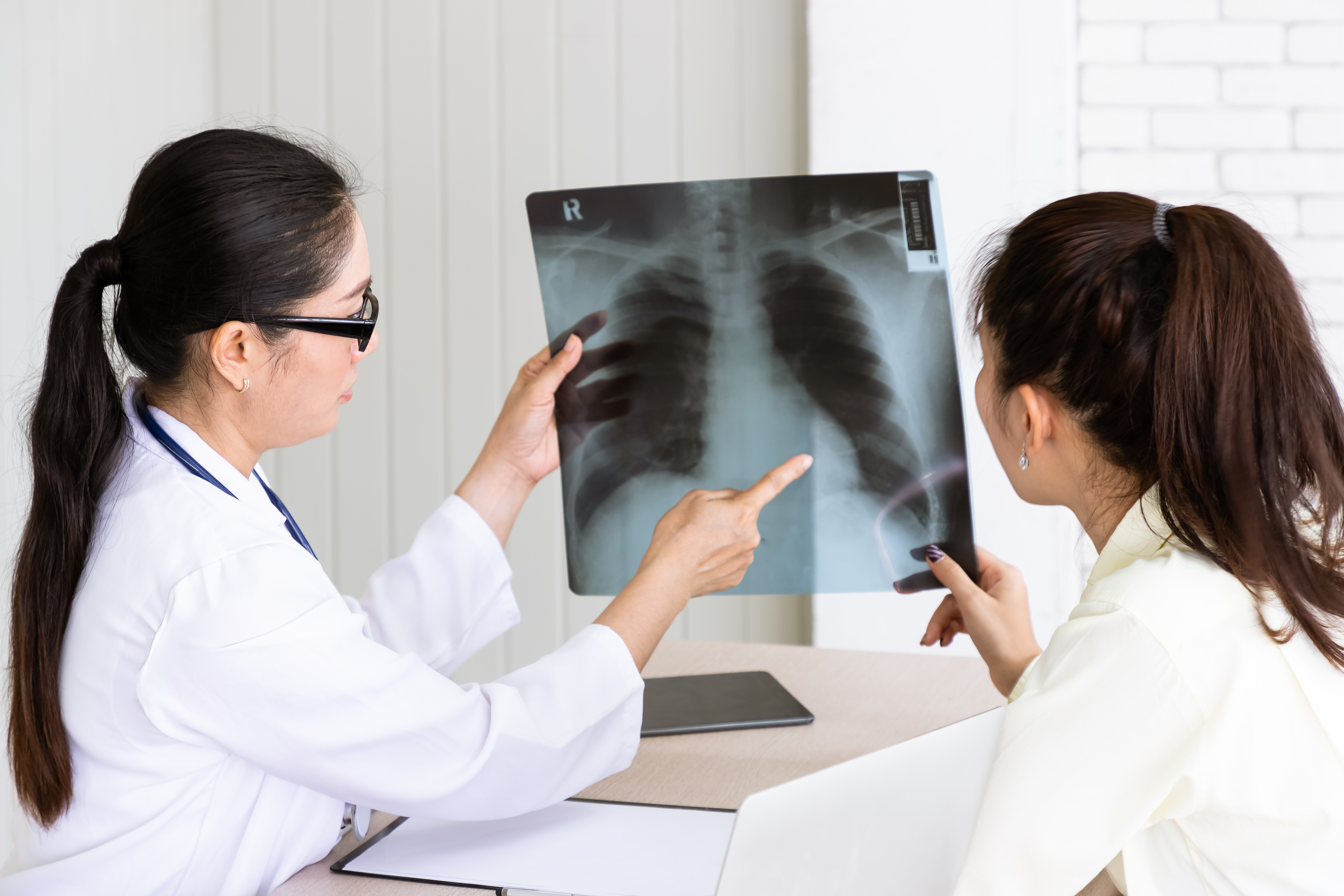 Doctor pointing at xray scan showing to girl with ponytail 