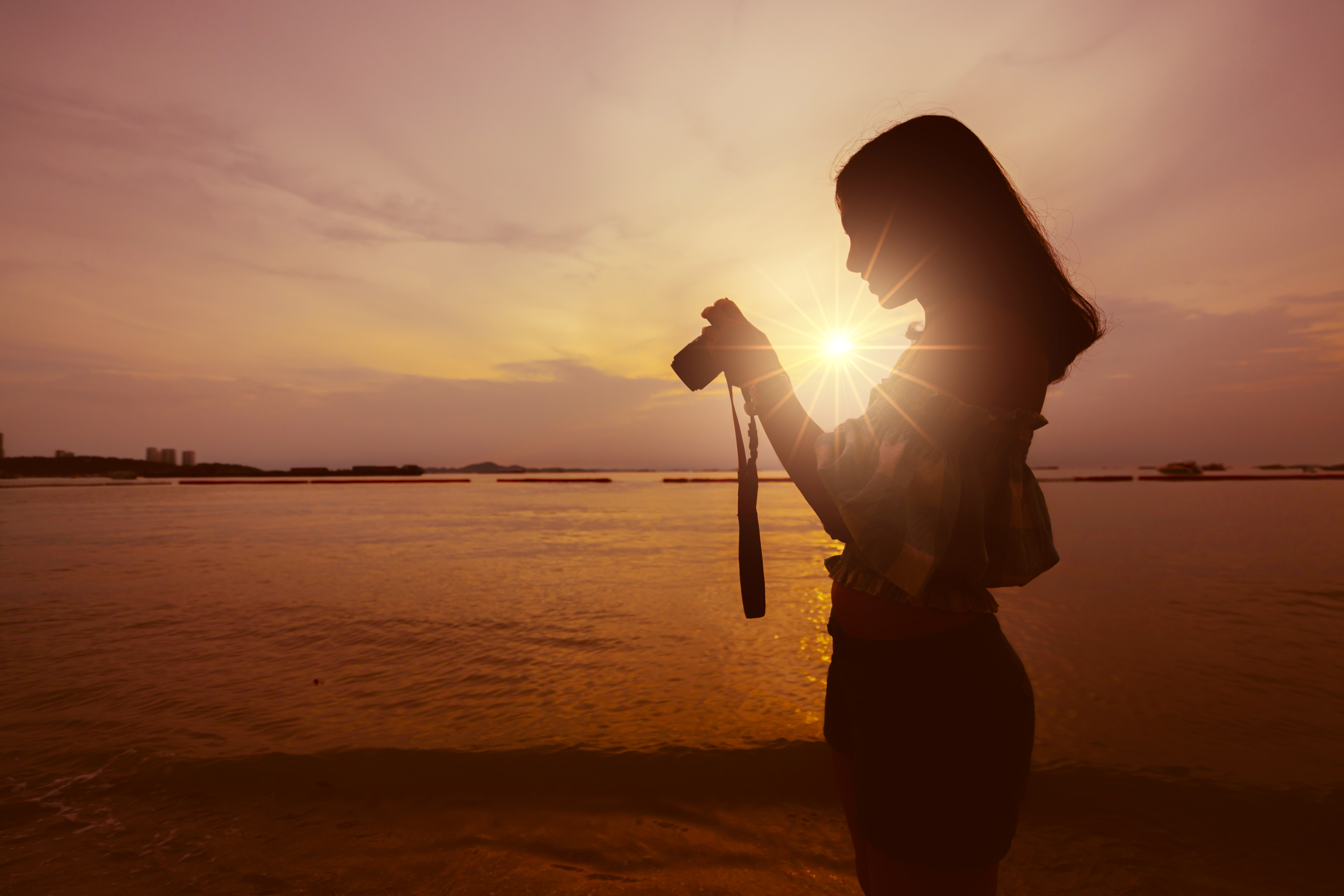 Girl taking photo with camera at sunset seaside 
