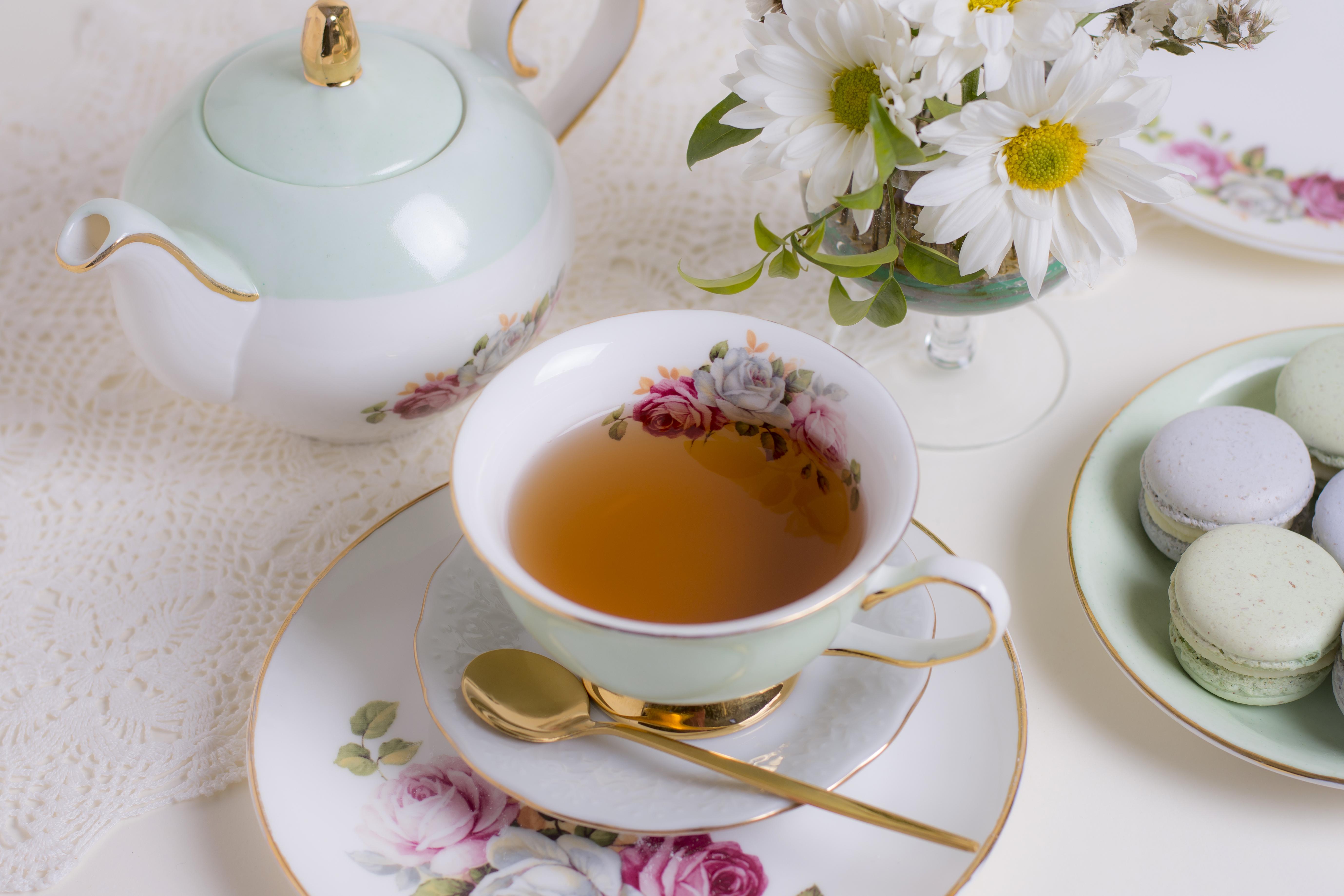 British tea with teacup and teapot on table with daisies and macaroon 