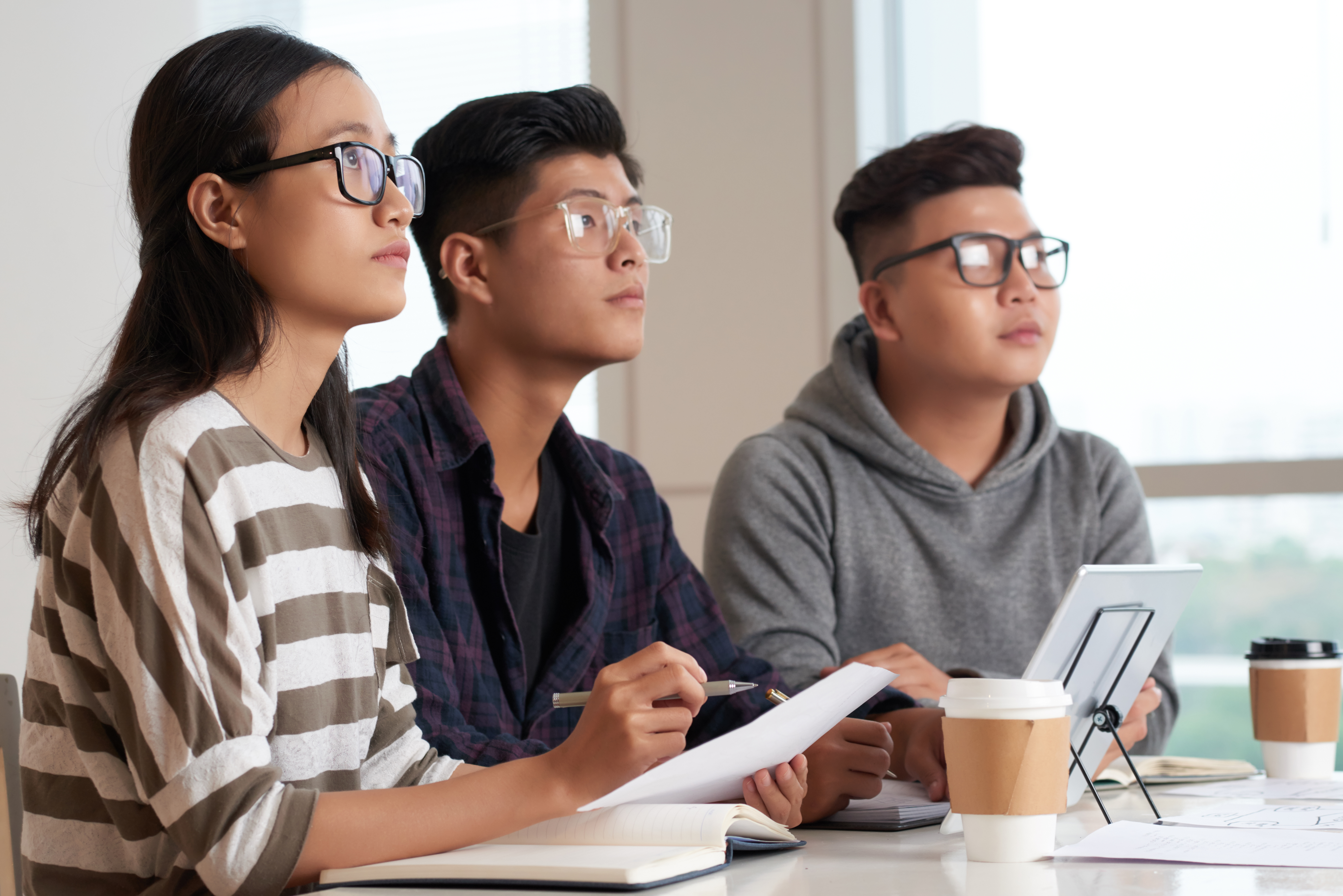 Three asian students with glasses taking classes 